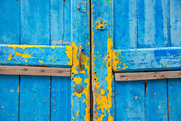 Blue antique wooden door. But some of the color was peeled off to see the old color that is yellow.