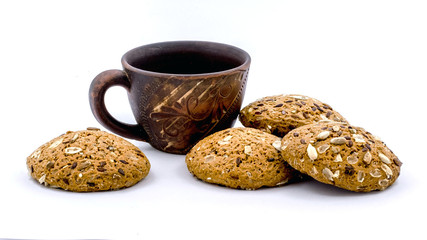 Coffee mug and oatmeal cookies with sunflower seeds on a white isolated background. Delicious and healthy cookies for coffee and tea_
