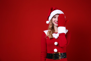 Studio shot of beautiful smiling young woman wearing sexy santa claus suit for Christmas. Attractive blonde female in tight red dress, new years eve. Copy space, isolated background, close up.