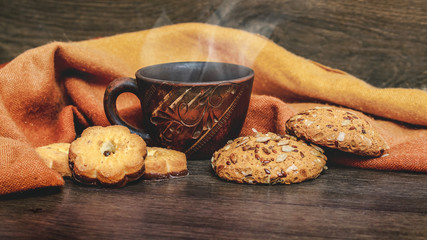 Clay cup with hot coffee and cookies on a wooden table_