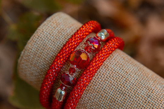 Beautiful, shiny, color bracelet with large beadwork beads. On a special stand for jewelry. Brown autumn foliage on the background.