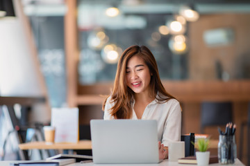 Portrait of young businesswoman watching at laptop and smiling 