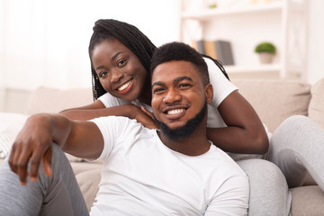 Portrait of smiling afro couple posing to camera at home