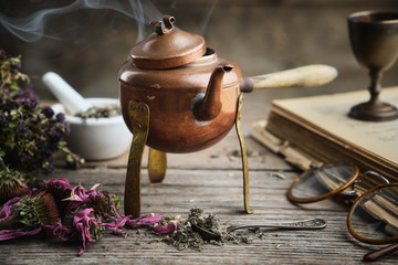 Old antique boiling teapot, dry coneflowers, old books, retro glasses and medicinal herbs.