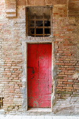 Fototapeta na wymiar Old weathered red door in a building