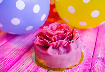 Pink cake Birthday, Valentines Day, presents and colorful balloons on a light pink wooden board. Concept celebration.