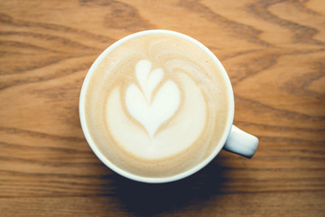Cup of cappuccino with latte art on wooden table. Top view.