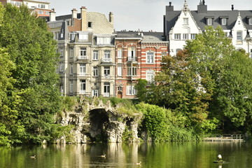 La fausse grotte en rocaille et derrière les maisons de maîtres au square Marie-Louise à Bruxelles