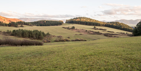 Fototapeta premium autumn hilly landscape with meadows, small fields, forest, hills and blue sky with clouds