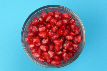 Red Pomegranate seed in glass on blue paper background