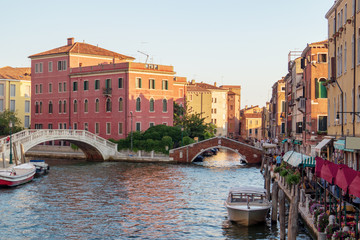 Fototapeta na wymiar Venice, Italy. Wide canal with bridges and boats and an outdoor cafe