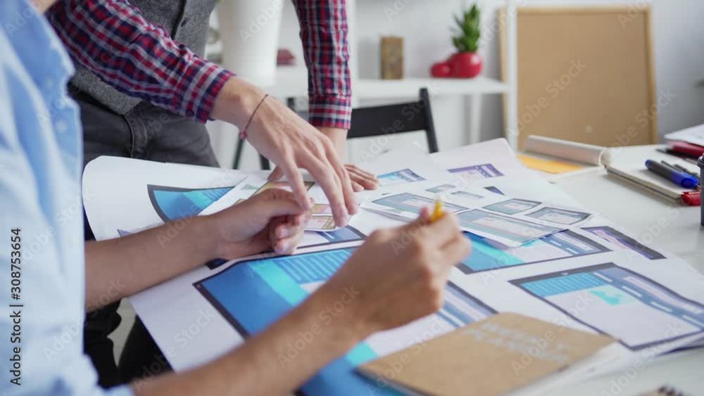Wall mural tilt down closeup of man explaining ideas to colleague at desk in office. two web designers or marke