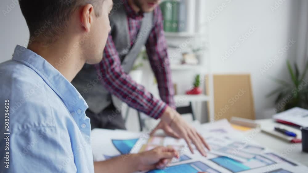 Wall mural tilt down closeup of two web designers or marketing professionals discussing website interface sampl