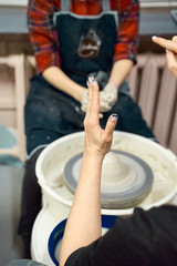 Woman teaches pottery making on potter's wheel, master class, workshop. Creative hobby concept. Earn extra money, side hustle