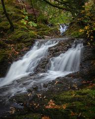 Tranquil autumn woodland scene with waterfall in Scottish highlands.Motion of flowing water.Fairytale forest scenery.Tranquil nature scene.