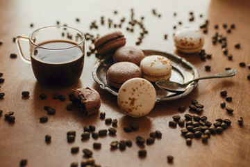 Coffee in glass cup and delicious macaroon cookies on vintage plate on wooden table with roasted...