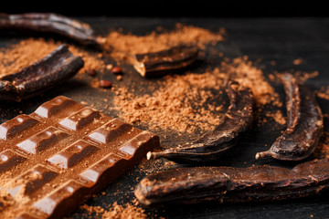 The pods of the carob chocolate bar on a black background.