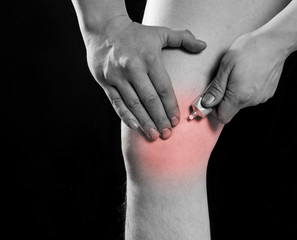 rubbing medicated ointment into the affected knee. black-and-white