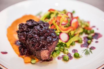 Roasted beef with berries sauce garnished with vegetables