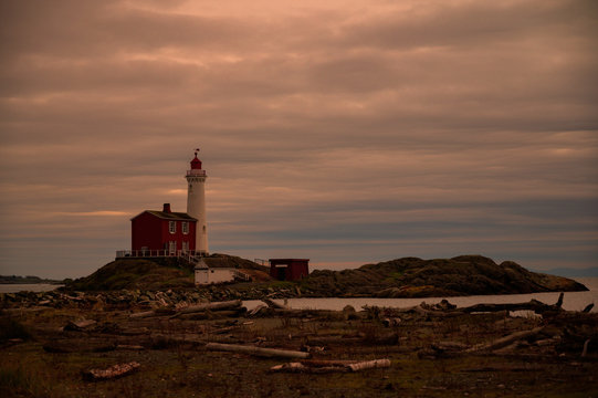 Stunning Lighthouse and Red Brick Building with Bay and Dramatic Clouds in Sky - Powered by Adobe