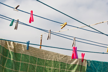 A clothespin hangs on the washing line. A rope with clean linen and clothes outdoors on the day of the laundry. Against the background of green nature and sky.