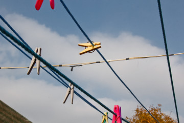 Fototapeta na wymiar A clothespin hangs on the washing line. A rope with clean linen and clothes outdoors on the day of the laundry. Against the background of green nature and sky.