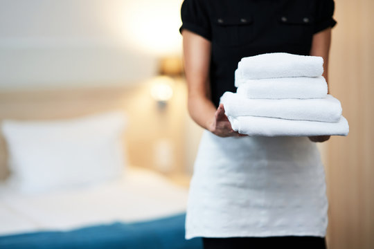Maid with fresh towels in hotel room