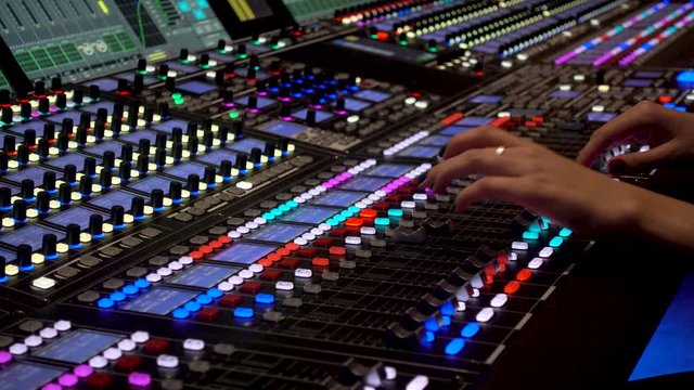 Close-up of a mixing console, the hand adjusts the faders Professional recording studio.