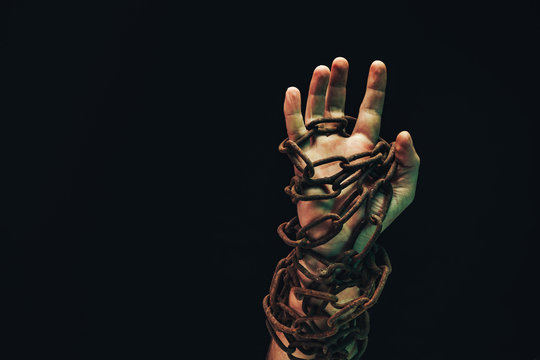 Human hand are chained in chains isolated on black background.