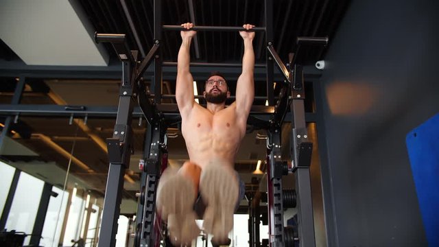 Ripped Shirtless Man Doing Pull-Ups in the Hardcore Gym. Abdominal excercise