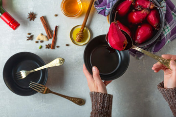 Boiled pears in mulled wine. Woman puts pears in a bowl.