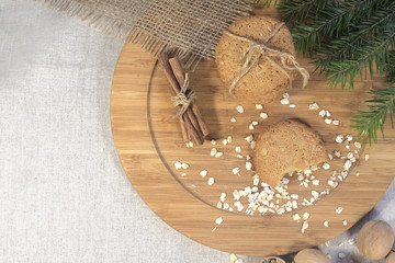 composition round oatmeal cookies, cinnamon sticks and sprig of spruce on a wooden board