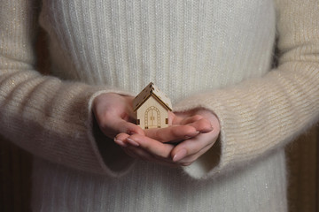 Fototapeta premium A small model of a wooden house stands on a hand. Concept image of my house. The project of a country house.