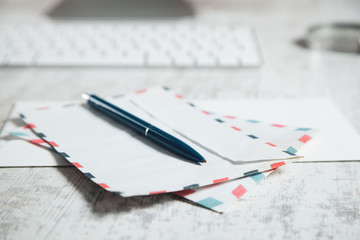 pen on letters with computer keyboard on desk