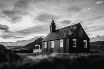 Kirche vor dramatischem Bergpanorama Island