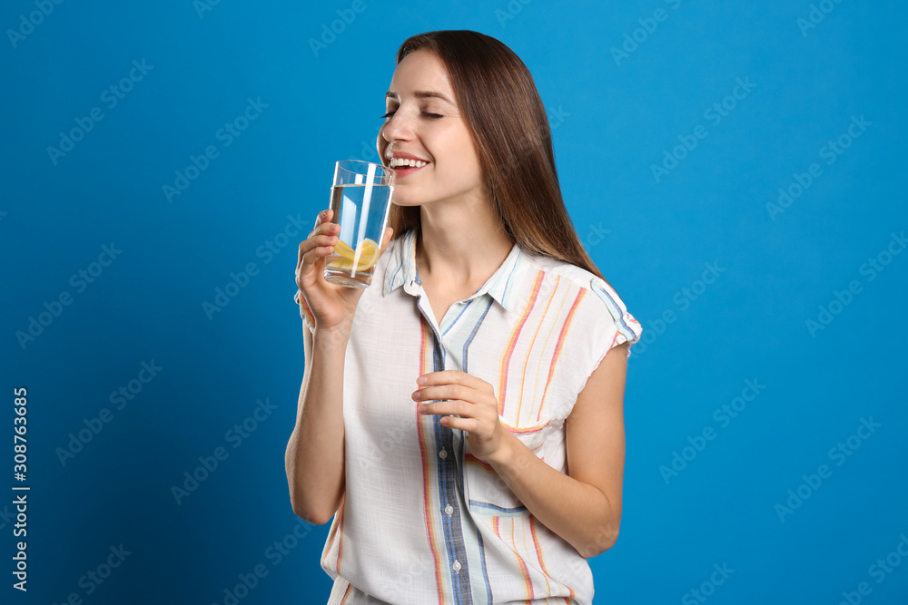 Canvas Prints Young woman drinking lemon water on light blue background