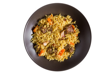 Pilaf with lamb, carrots, onions, garlic, pepper and barberry. A traditional dish of Asian cuisine. Selective focus, isolated on brown plate. Top view.