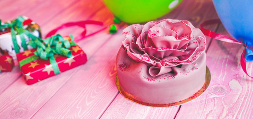 Pink cake Birthday, Valentines Day, presents and colorful balloons on a light pink wooden board. Concept celebration.