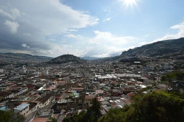 Fototapeta na wymiar Colonial City of Quito, sunny afternoon on the tile roofs, several temples and ancient churches, in the background the monument to the Virgin on the hill called 