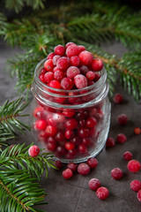 Frozen cranberry berry in a jar on the table decorated with branches of the Christmas tree. Christmas winter time