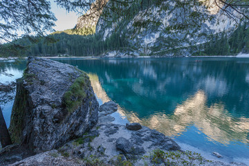 Giant boulders on the shores of Lake Braies on which the mountains are reflected, South Tyrol, Italy. Concept: relaxation in nature, famous natural places, film sets