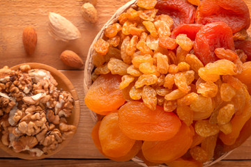 Mix of dried fruits, assorted nuts and seeds on a wooden table. Close-up. Top view