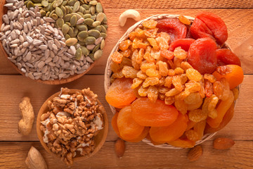 Mix of dried fruits, assorted nuts and seeds on a wooden table. Close-up. Top view