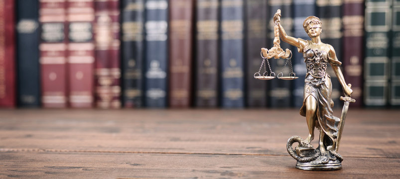 Scales of Justice, Lady Justice and Law books on a  wooden background.