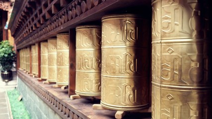 Tibetan style brass prayer wheels closeup shot, selected focus at the closer wheels and blurred background.
