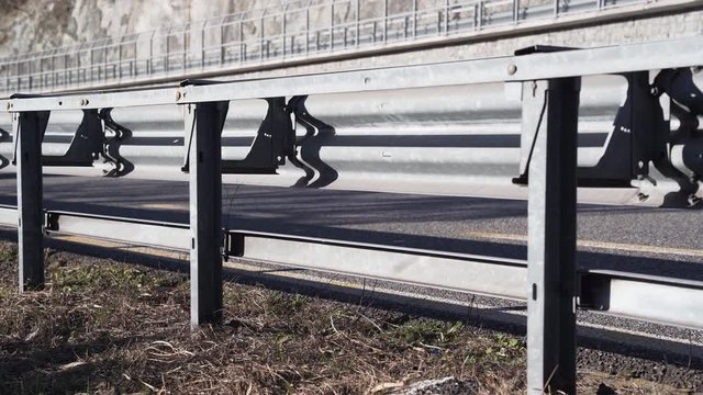 Car passing on a highway seen from the other side of the guard rail