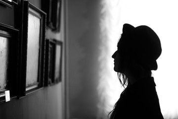 Silhouette of a young woman looking at a picture in an art gallery or museum. Black and white. Profile