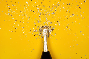 Bottle of champagne with splash of confetti. Flat lay style. © Anna Efetova
