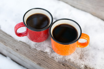 Two coffee mugs on the porch of a wooden house. Autumn and winter season.