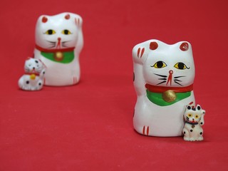 Four little Maneki Neko, Japanese lucky cats, amulets that bring good luck, health and happiness. Two cats in the foreground, that look like father (mother) and son, are well focused.